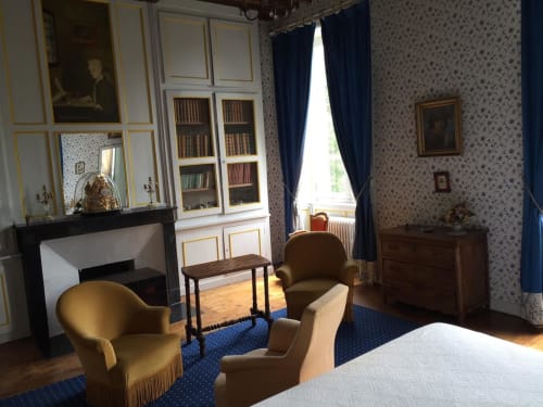 La Chambre Bleue du Château d'Asnières en Bessin avec mobilier d'époque, cheminée, bibliothèque et vue sur le jardin