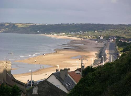 Coastal beach view with sandy shore and residential buildings at Chateau d'Asnieres en Bessin, Normandy