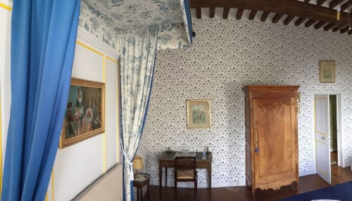 Chambre bleue du Château d'Asnières en Bessin avec papier peint fleuri, armoire en bois, bureau et mobilier d'époque