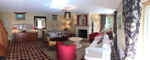 Elegant living room at Chateau d'Asnieres en Bessin cottage with red armchairs, fireplace, and garden view