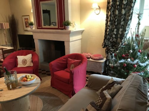 Cozy living room at Chateau d'Asnieres cottage with red armchairs, fireplace, decorated Christmas tree, and garden views