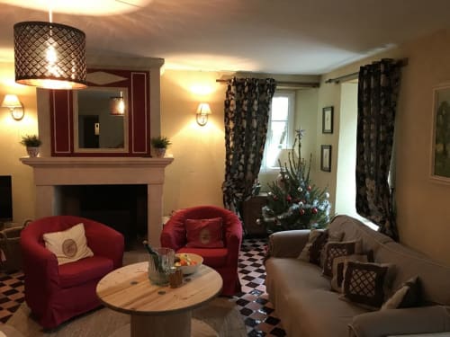 Elegant living room at Chateau d'Asnieres en Bessin cottage with red armchairs, fireplace, and holiday décor