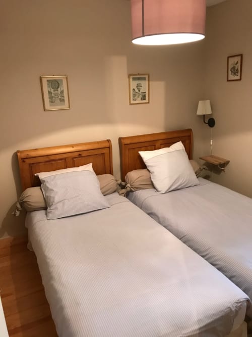 Two twin beds with white linens in a cottage bedroom at Chateau d'Asnieres en Bessin, France, with wooden headboards and
