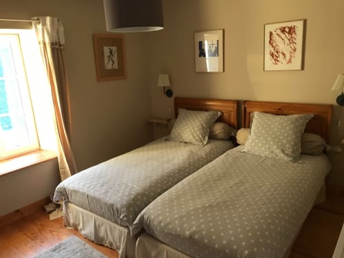 Twin bedroom with polka dot bedding and wooden headboards at Chateau d'Asnieres en Bessin cottage, garden view visible