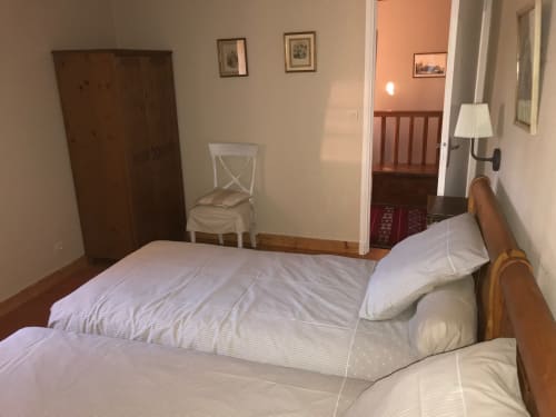 Bedroom at Chateau d'Asnieres en Bessin cottage with twin beds, wooden wardrobe, and garden view