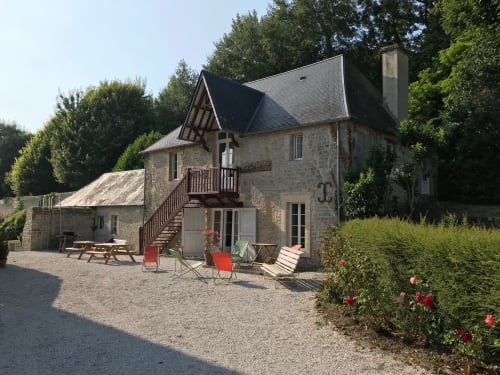 Stone cottage at Chateau d'Asnieres en Bessin with garden seating area and pink roses, Normandy France