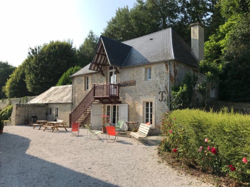 Chateau d'Asnieres en Bessin - Stone manor house with dark roof, courtyard seating, and flowering gardens in Normandy