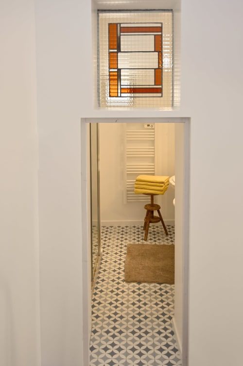 Bathroom doorway at Mas des Artistes cottage in Mouriès with geometric tile floor, wooden stool, and yellow towels on rack