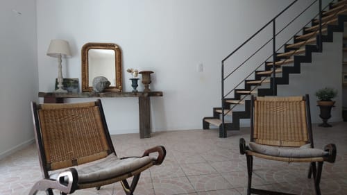 Mas des Artistes cottage sitting area with wicker chairs, console table with mirror, and modern staircase in Mouriès