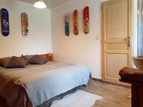 Chambre double cosy à l'Aux Pays Des Sucs avec planches à roulettes décorées, porte en bois et literie rayée à Saint-Hostien