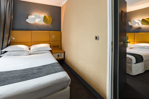 Modern hotel connecting rooms at Hotel Residence Europe & Spa in Clichy with gold headboards and contemporary lighting