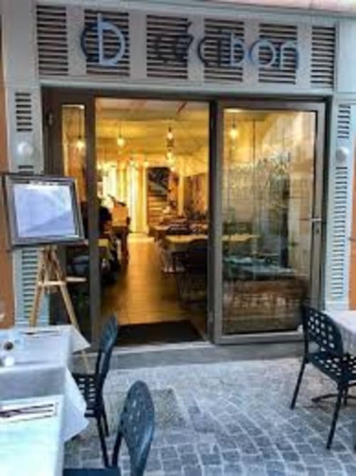 Saint Martin B&B storefront in Ollioules with glass doors, outdoor seating, and warm interior lighting