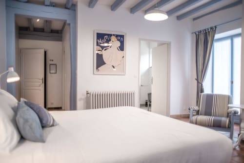 Chambre élégante au Gîte Le Pignié à Lescure-d'Albigeois avec lit blanc, détails bleus et vue sur le jardin