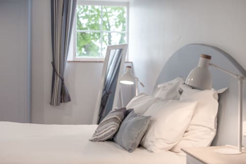 Chambre lumineuse au Gîte Le Pignié à Lescure-d'Albigeois avec literie blanche, oreillers rayés, tête de lit cintrée et jardin