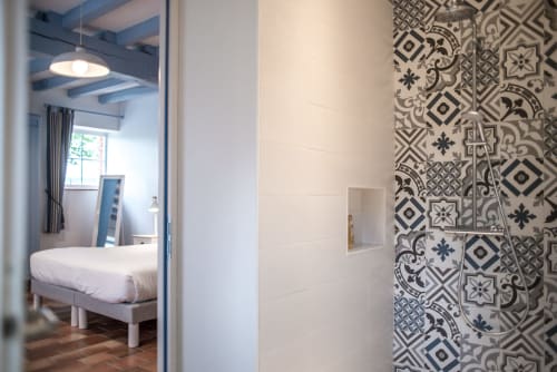 Entrée de chambre moderne au Pignié avec salle de bain aux carrelages noir et blanc, vue sur le jardin.