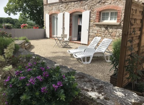 Terrasse du gîte Le Pignié à Lescure-d'Albigeois avec transats, fleurs et façade en pierre