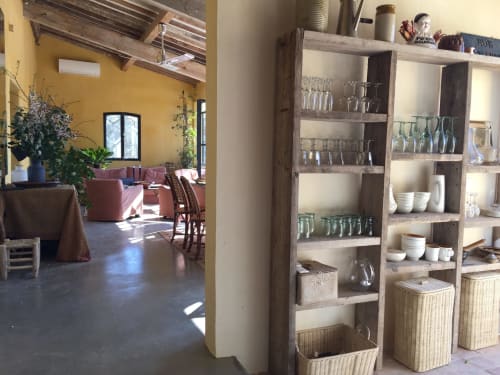 Saint Martin BnB lounge with yellow walls, rustic shelving, glassware, and pink seating in Ollioules