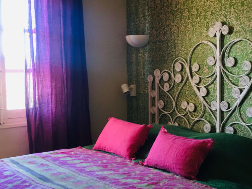 Vibrant bedroom at Saint Martin B&B in Ollioules with ornate headboard, hot pink pillows, and purple curtains