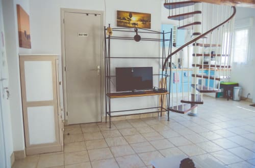 Séjour ouvert au Gîte Angkor avec unité TV, escalier hélicoïdal et équipements modernes aux Gîtes