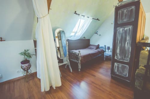 Chambre mansardée aux gîtes des châteaux, Vallières-les-Grandes, avec lit, miroir, plante et fenêtres mansardes voilées