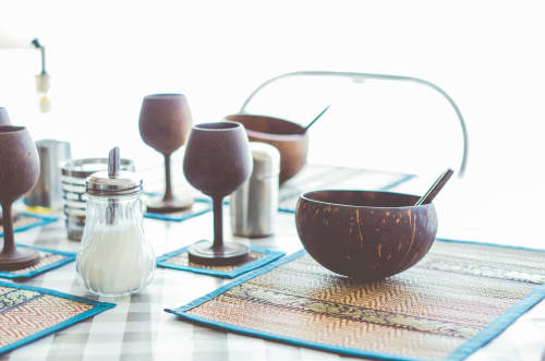 Installation tropicale aux gîtes des châteaux avec bols en noix de coco, verres à vin et sets de table bleus