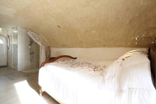 Chambre du gîte Studio Tana avec literie blanche, lit en bois et salle d'eau attenante aux gîtes des châteaux
