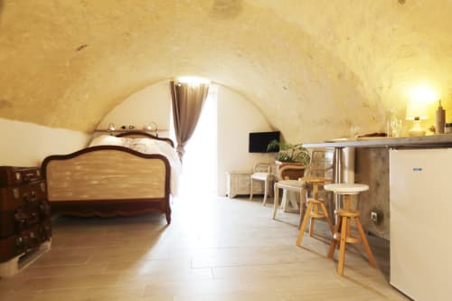 Le gîte Studio Tana aux gîtes des châteaux dispose d'un plafond en pierre voûté, un lit en bois, une kitchenette et des places assises au bar
