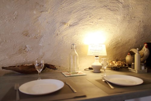 Ambiance intime de salle à manger au gîte avec couverts dressés, bouteille de vin et décor rustique