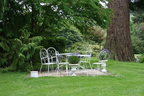 White ornate garden furniture under ancient trees at La Chatellenie B&B in Saint Aubin le Cauf, France