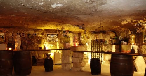 Underground wine cellar at Les gîtes des châteaux with barrels, artwork, and ambient lighting in Vallières-les-Grandes