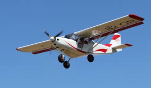Small red and white aircraft flying over Vallières-les-Grandes, France near Les gîtes des châteaux
