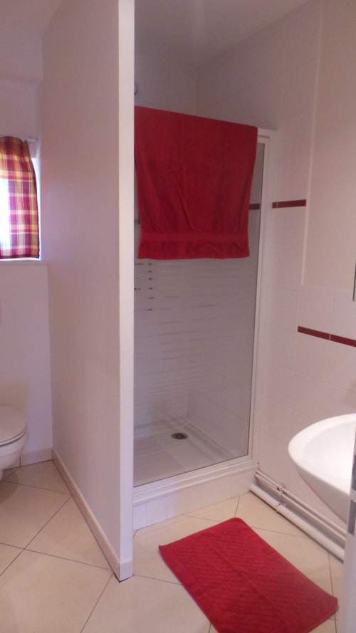 Salle de bain moderne du Studio Bouleau à La Croix De La Jarrie, avec douche vitrée, serviette rouge et baignoire assortie
