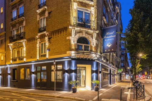 Hotel Residence Europe & Spa exterior at night in Clichy with illuminated brick facade and elegant storefront