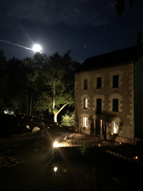 Moulin De La Chevrière la nuit sous le clair de lune, bâtiment en pierre aux fenêtres illuminées à Saché, France