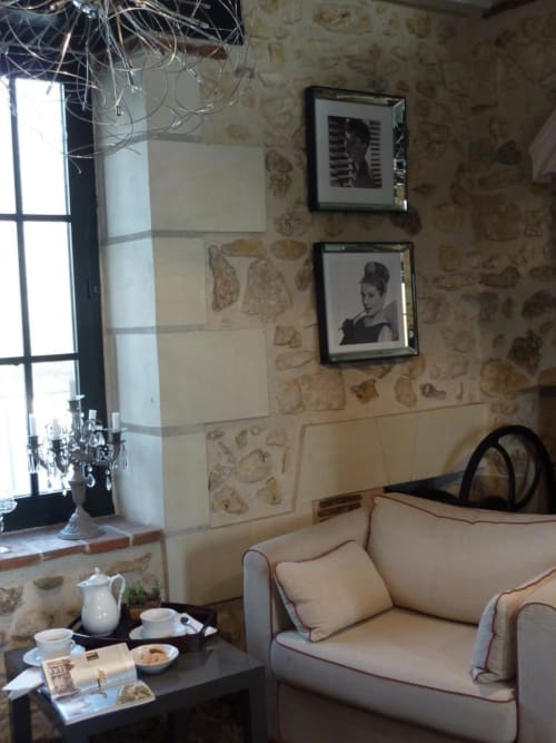 Salon cosy du Moulin De La Chevrière avec canapé crème, portraits encadrés, papier peint à motifs et service à thé près de la fenêtre
