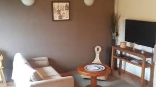 Salon douillet du Gite de la Tannerie à Dinan avec canapé beige, table basse en bois et TV écran plat