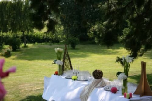 Elegant outdoor dining setup at La Chatellenie in Saint Aubin le Cauf, with decorated table, flowers, and lush garden