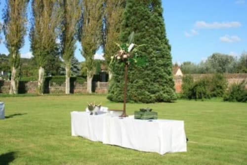 White table with floral arrangement in manicured gardens at La Chatellenie B&B, Saint Aubin le Cauf