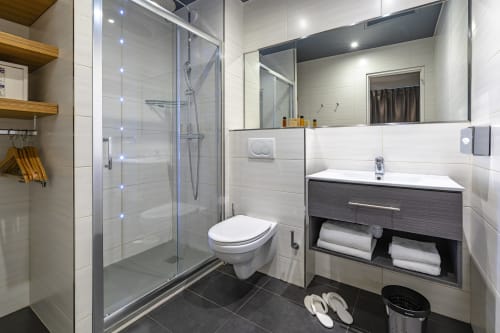 Modern bathroom in Hotel Residence Europe & Spa, Clichy with shower, toilet, vanity sink and towel storage