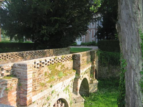 Ancient stone walls with ivy at La Chatellenie B&B in Saint Aubin le Cauf, France, with manor house visible