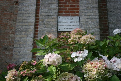 Memorial plaque for Alexandre Alekhine at La Chatellerie in Saint Aubin le Cauf, surrounded by pink hydrangeas