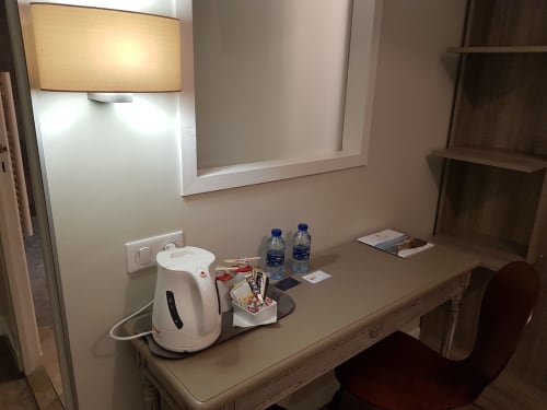 Bureau de la chambre standard de l'Hôtel Au Bon Coin avec bouilloire, bouteilles d'eau et équipements à Biarritz