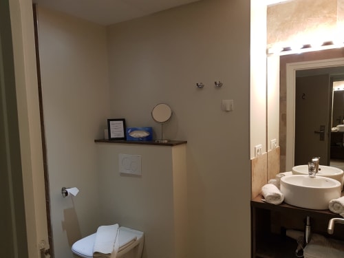 Modern bathroom at Hotel Au Bon Coin Biarritz with dual vessel sinks, toilet, and marble accents