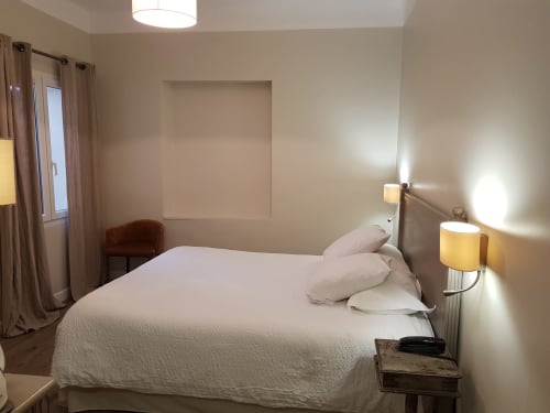 Chambre Supérieure moderne à l'Hôtel Au Bon Coin à Biarritz avec literie blanche, lampes de chevet et rideaux avec vue sur la ville