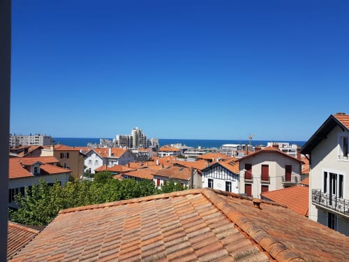 Vue depuis la terrasse de l'Hôtel Au Bon Coin : toits en tuiles rouges, bâtiments blancs et horizon bleu de la Méditerranée à Biarritz
