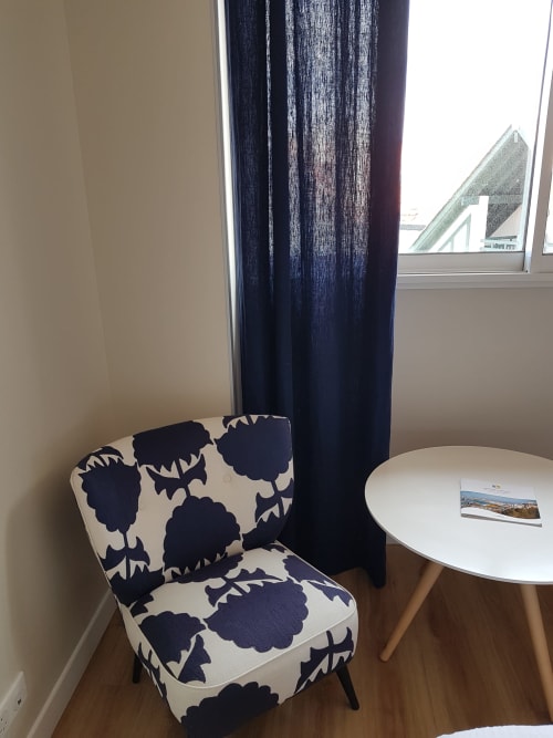 Coin séjour élégant de la Chambre Deluxe à l'Hôtel Au Bon Coin, Biarritz, avec fauteuil à motifs et table ronde près de la fenêtre
