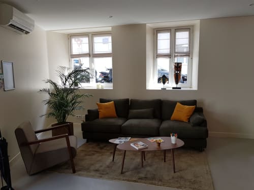 Modern lounge at Hotel Au Bon Coin in Biarritz with black sofa, orange pillows, and natural light