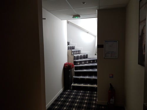 Stairwell at Hotel Au Bon Coin in Biarritz with black and white checkered flooring and red flowers