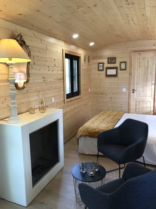 Chambre moderne du Moulin De La Chevrière à Saché avec murs en bois, cheminée et fauteuils noirs