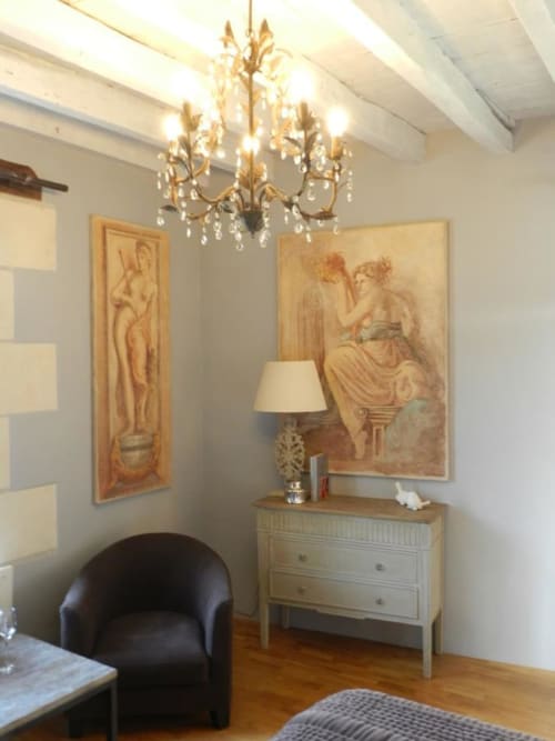Chambre élégante au Moulin De La Chevrière avec art classique, lustre doré, commode en bois clair et fauteuil noir